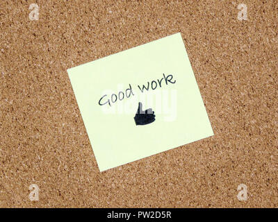 A yellow sticky note with good work written on it on a cork board background Stock Photo