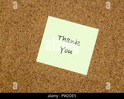 A yellow sticky note with thank you written on it on a cork board background Stock Photo