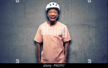 Black man wearing bike helmet stressful, terrified in panic, shouting exasperated and frustrated. Unpleasant gesture. Annoying work drives me crazy Stock Photo