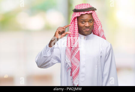Young arabic african man wearing traditional keffiyeh over isolated background smiling and confident gesturing with hand doing size sign with fingers  Stock Photo