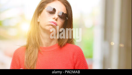 Middle age woman wearing heart sunglasses with sleepy expression, being overworked and tired Stock Photo