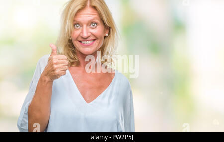 Middle age blonde business woman over isolated background doing happy thumbs up gesture with hand. Approving expression looking at the camera with sho Stock Photo