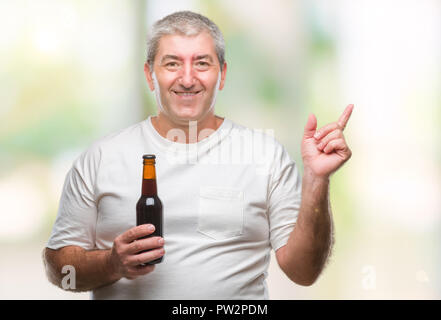 Handsome senior man drinking beer bottle over isolated background very happy pointing with hand and finger to the side Stock Photo