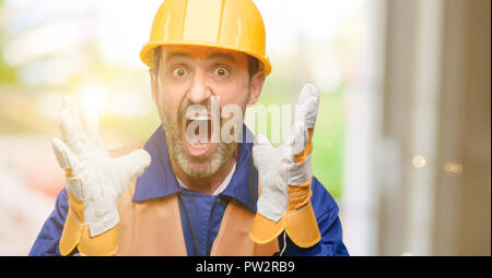 Senior engineer man, construction worker stressful keeping hands on head, terrified in panic, shouting Stock Photo