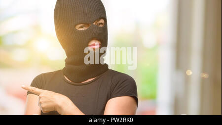 Burglar terrorist woman wearing balaclava ski mask pointing away side with finger Stock Photo