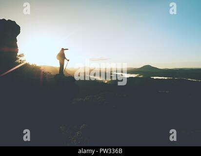 Hiker climbed on rock above foggy valley. Hrensko range, Czech Republic, 21st of Seprtember 2018.  Man watch over misty morning valley to bright morni Stock Photo