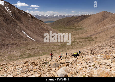 Trekkers descend from 4,800m Bel Airyk Pass with Zorkul Lake in background on trek from Keng Shiber to Kara Jilga, Pamir Mountains, Tajikistan. Stock Photo