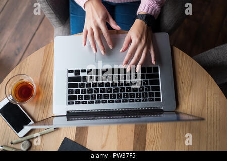 Woman is working by using a laptop computer on wooden table. Hands typing on a keyboard. Stock Photo