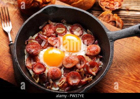 Cooked egg and sausages on rying pan, tasty english breakfast on wooden background Stock Photo