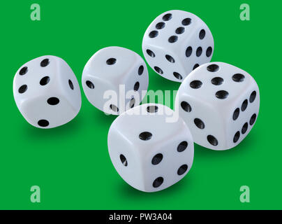 Five white dices of different size in a craps game, yatzee or any kind of dice game against a green background Stock Photo