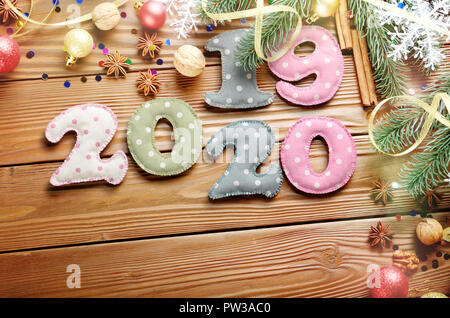 Colorful stitched digits 2019 2020 of polkadot fabric with Christmas decorations flat lyed on wooden background Stock Photo