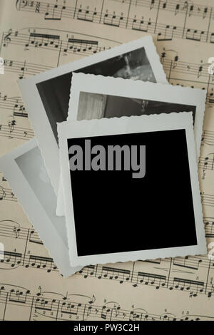 A stack of vintage photos on an old piece of sheet music. Add your own photo or text. Stock Photo