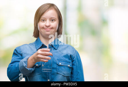 Young adult woman with down syndrome drinking water over isolated background with a happy face standing and smiling with a confident smile showing tee Stock Photo