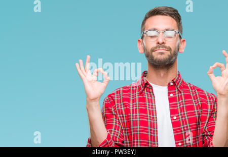 Young handsome man over isolated background relax and smiling with eyes closed doing meditation gesture with fingers. Yoga concept. Stock Photo