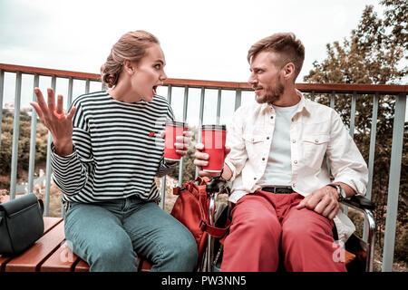 Young woman using gestures while talking to her attentive friend Stock Photo