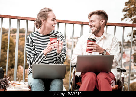 Cheerful freelancers sitting with laptops and enjoying their coffee Stock Photo