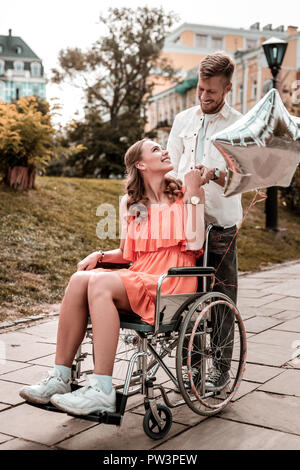 Loving girl sitting in wheelchair with her boyfriend indoor Stock Photo ...