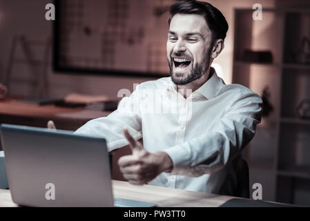 Cheerful bearded man looking at laptop Stock Photo