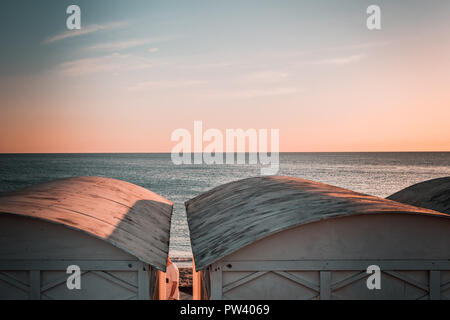 Details from lovely white beach huts in Europe. Windy sunny day, blue hazy mood, winter sunset to dusk moment. Peacefull day ending, Curved rooftops. Stock Photo