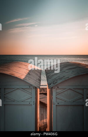 Beautiful white Bathing houses on the sandy beach. Empty shelters on a sunny but moody day. Seaside architecture, colored paint, maze-like labyrinth. Stock Photo