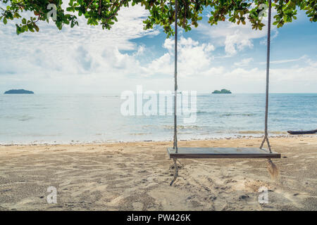 Wooden swing chair hanging on tree near beach at island in Phuket, Thailand. Summer Vacation Travel and Holiday concept. Stock Photo