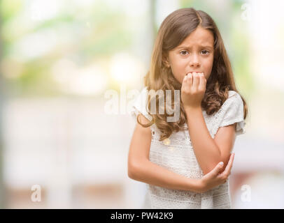 Brunette hispanic girl looking stressed and nervous with hands on mouth biting nails. Anxiety problem. Stock Photo