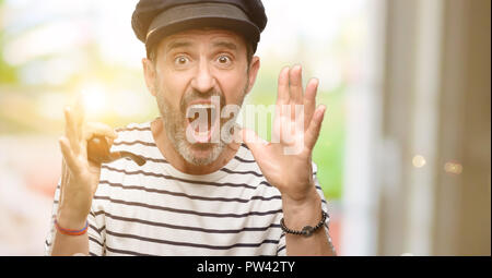 Sailor captain man smoking a tobacco pipe stressful keeping hands on head, terrified in panic, shouting Stock Photo