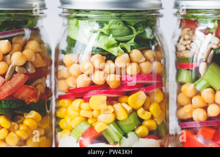 Three glass jars with layering various vegan salads for healthy lunch. Extrem close up. The concept of fitness and vegetarian food. Stock Photo