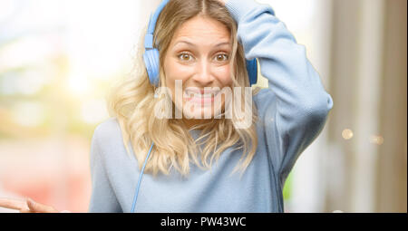 Young beautiful woman listening to music pointing away side with finger Stock Photo