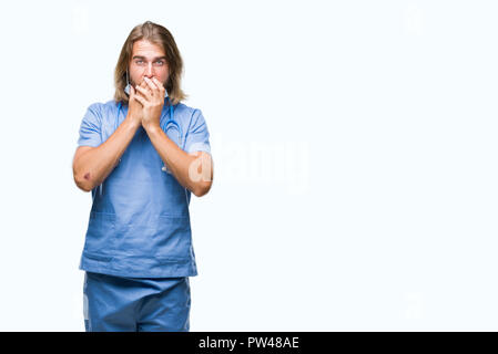 Young handsome doctor man with long hair over isolated background shocked covering mouth with hands for mistake. Secret concept. Stock Photo