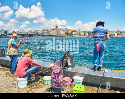 Citizens fishing in Eminonu Pier with a view of the Karakoy district skyline in the background. Istanbul, Turkey. Stock Photo