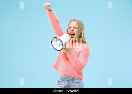 Teen girl making announcement with megaphone at blue studio Stock Photo