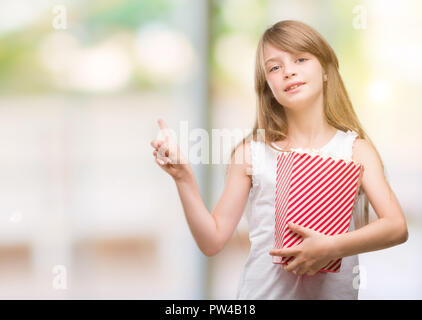 Young blonde toddler holding popcorn pack with a happy face standing ...