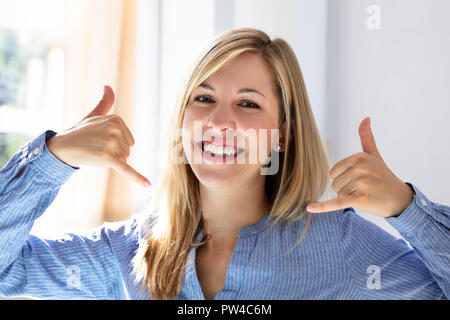 Portrait Of A Happy Young Businesswoman Making Call Me Gesture Stock Photo