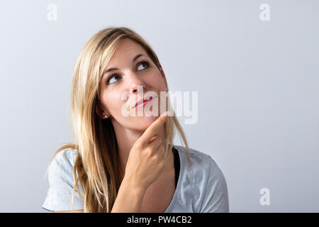 Portrait Of A Young Thoughtful Woman On Grey Background Stock Photo