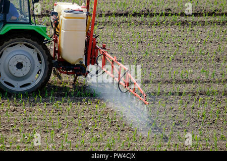 Tractor spraying pesticide on a field with young plants Stock Photo