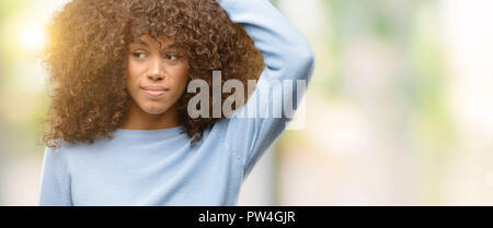 African american woman wearing a sweater confuse and wonder about question. Uncertain with doubt, thinking with hand on head. Pensive concept. Stock Photo