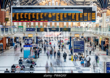 Busy passengers catching their trains at Liverpool Street Station in London. The long exposure captures the moving people as a series of blurs. Stock Photo