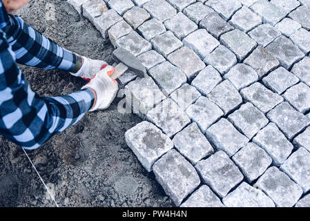 industrial worker installing pavement rocks, cobblestone blocks on road pavement Stock Photo