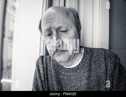 Senior man in his 60s feeling desperate sad looking throughout the balcony worried depressed thoughtful and lonely at home in Aging Depression Mental  Stock Photo