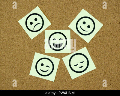 A  few yellow sticky notes with smiley faces on them on a cork board background Stock Photo