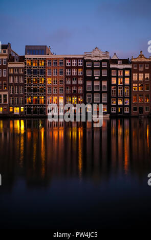 Buildings reflecting on calm canal against blue sky at dusk Stock Photo