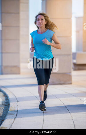 Portrait of confident female athlete running on footpath in city Stock Photo