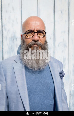 Portrait of hipster man with beard standing against wall during sunny day Stock Photo