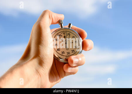 Cropped hand of man holding stopwatch against sky Stock Photo