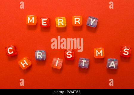 words merry christmas made of colorful blocks on red background. Flat lay, top view - holidays, winter, christmas and new year celebration concept Stock Photo