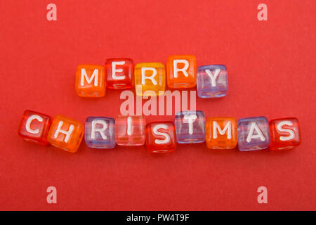 words merry christmas made of colorful blocks on red background. Flat lay, top view - holidays, winter, christmas and new year celebration concept Stock Photo
