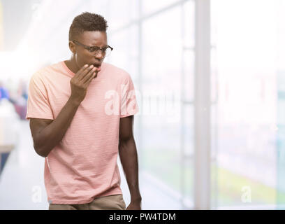 Young african american man wearing pink t-shirt touching mouth with hand with painful expression because of toothache or dental illness on teeth. Dent Stock Photo