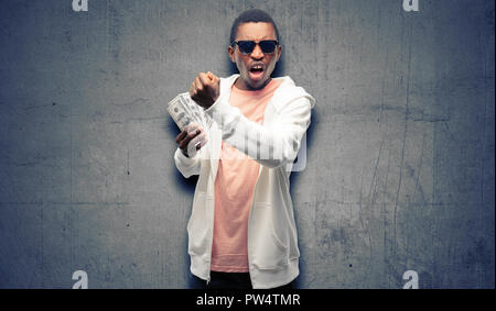 African man holding dollar bank notes irritated and angry expressing negative emotion, annoyed with someone Stock Photo