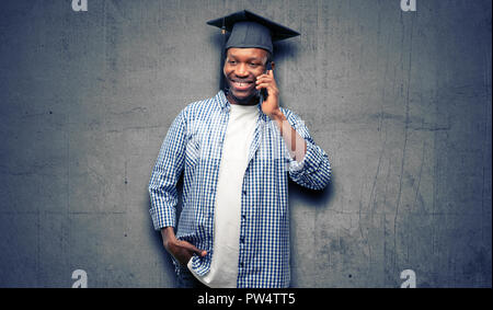 Young african graduate student black man happy talking using a smartphone mobile phone Stock Photo